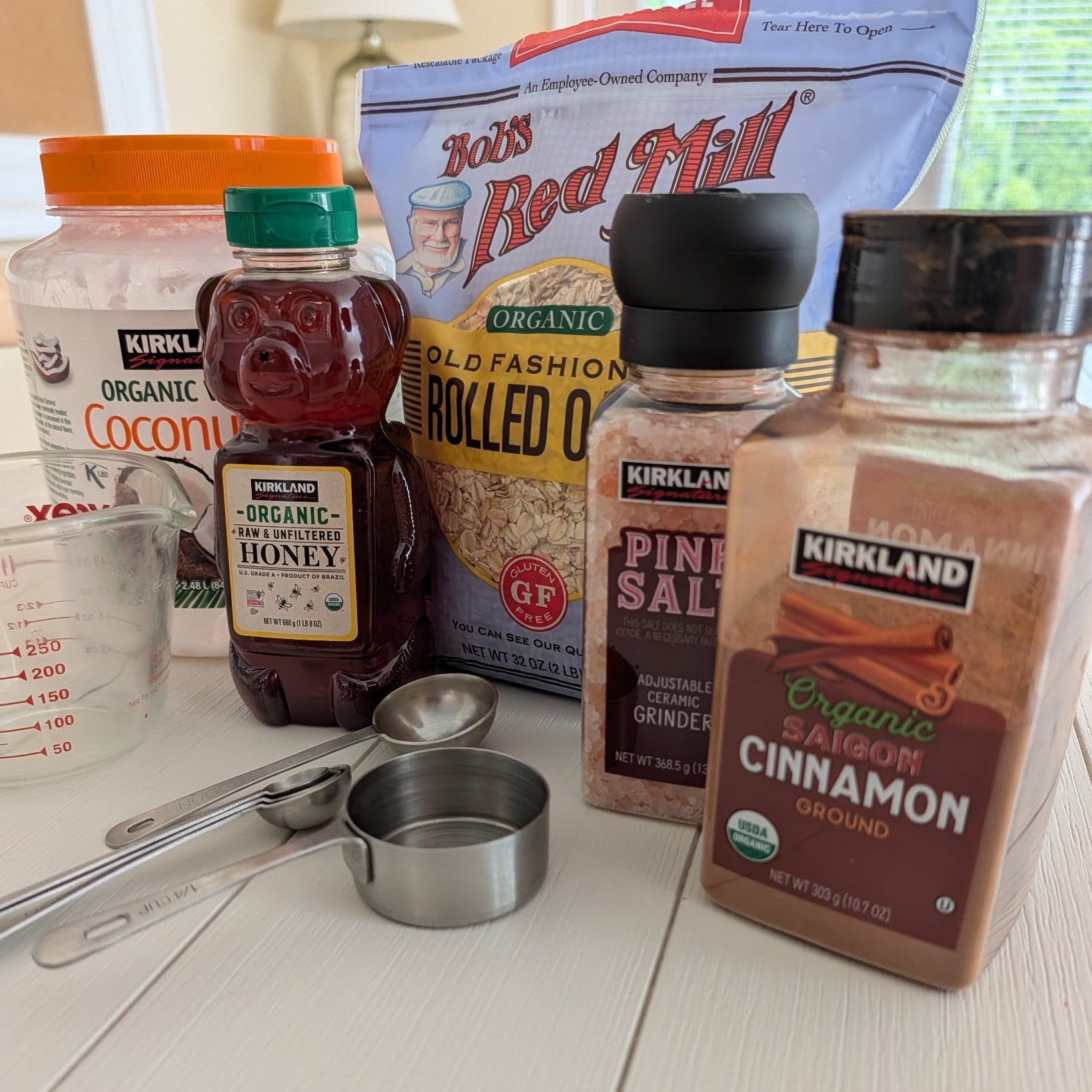 Kitchen ingredients including Kirkland Organic Cinnamon, Bob's Red Mill Organic Rolled Oats, and Kirkland Organic Pine Salt on a white countertop.